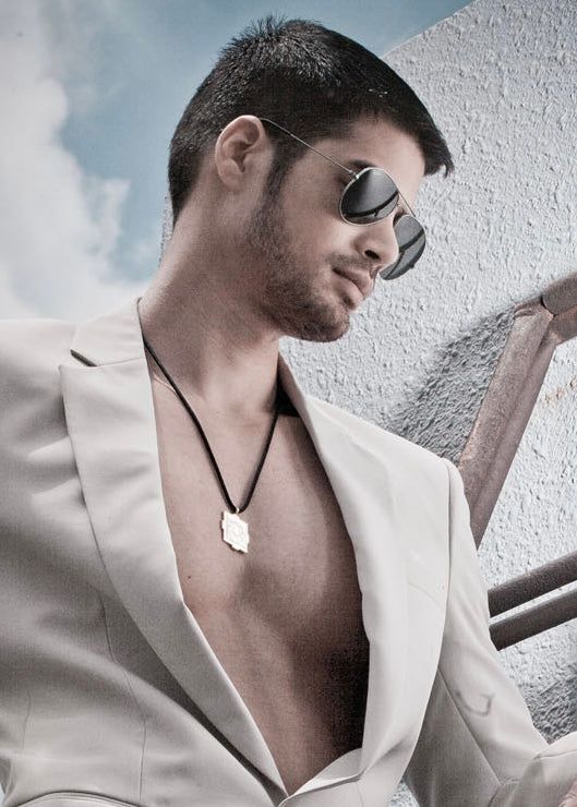 Man wearing sunglasses, a mandala necklace and a white suit with a blurred background