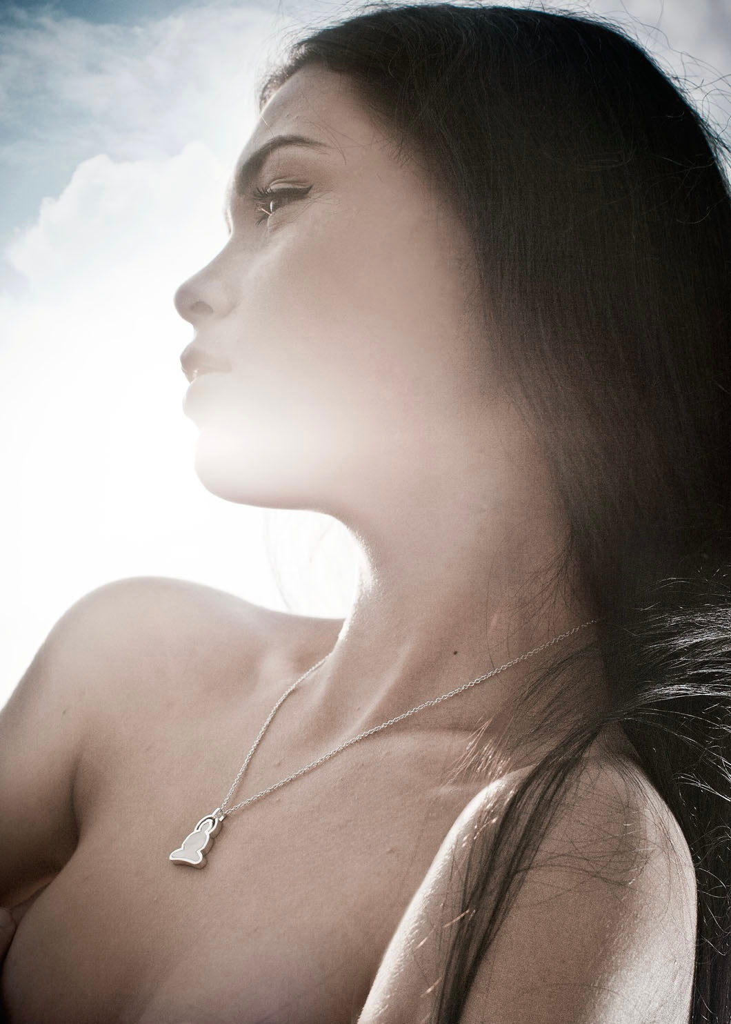 Close-up of a woman wearing a necklace with a Buddha pendant against a blurred background