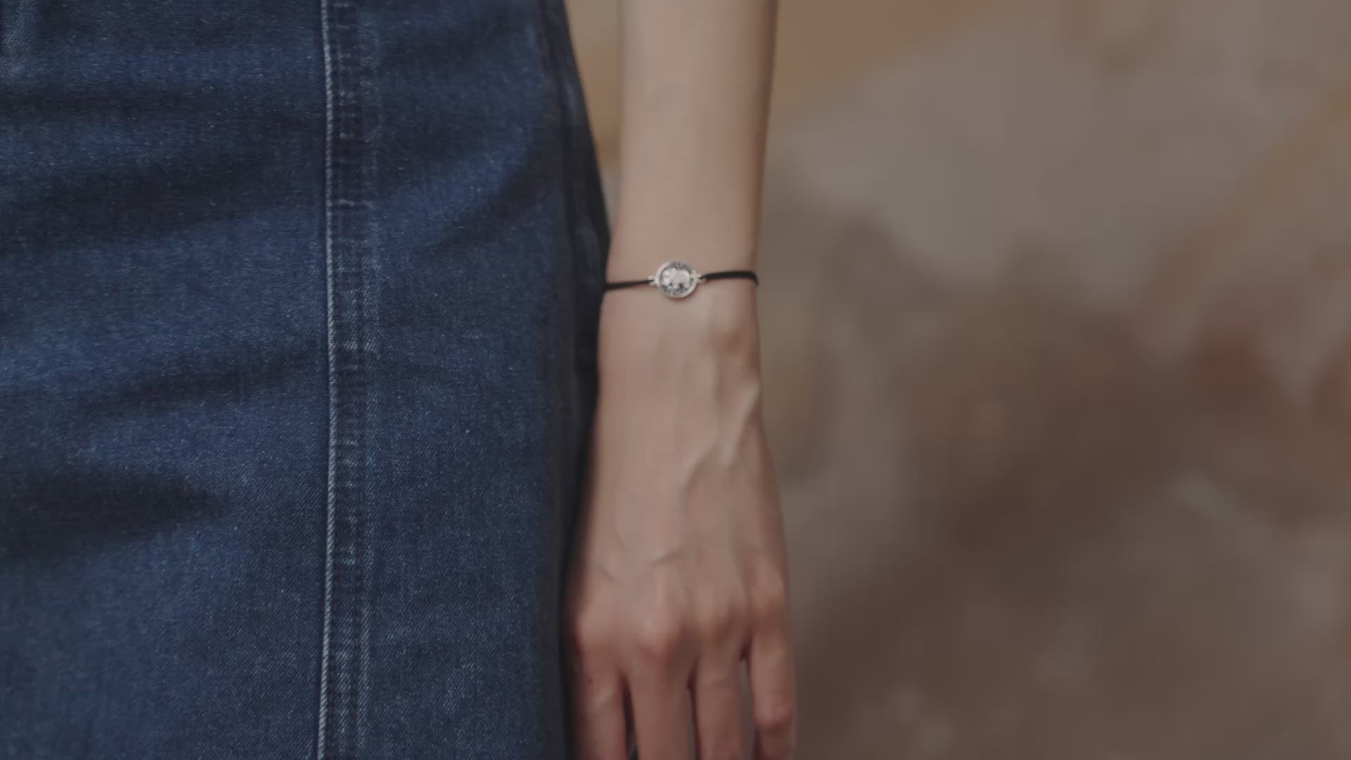 Video of a female model wearing a bracelet with a silver elephant charm